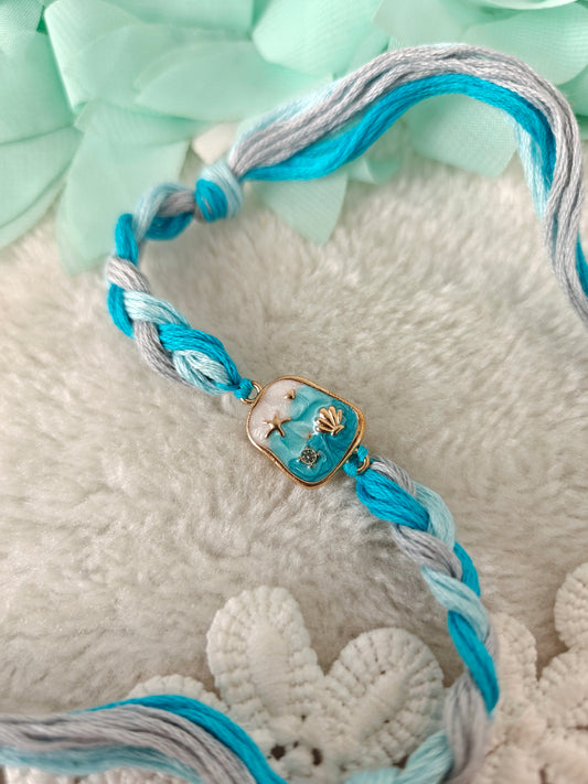 aqua ocean themed rakhi with shell charm and braided blue threads