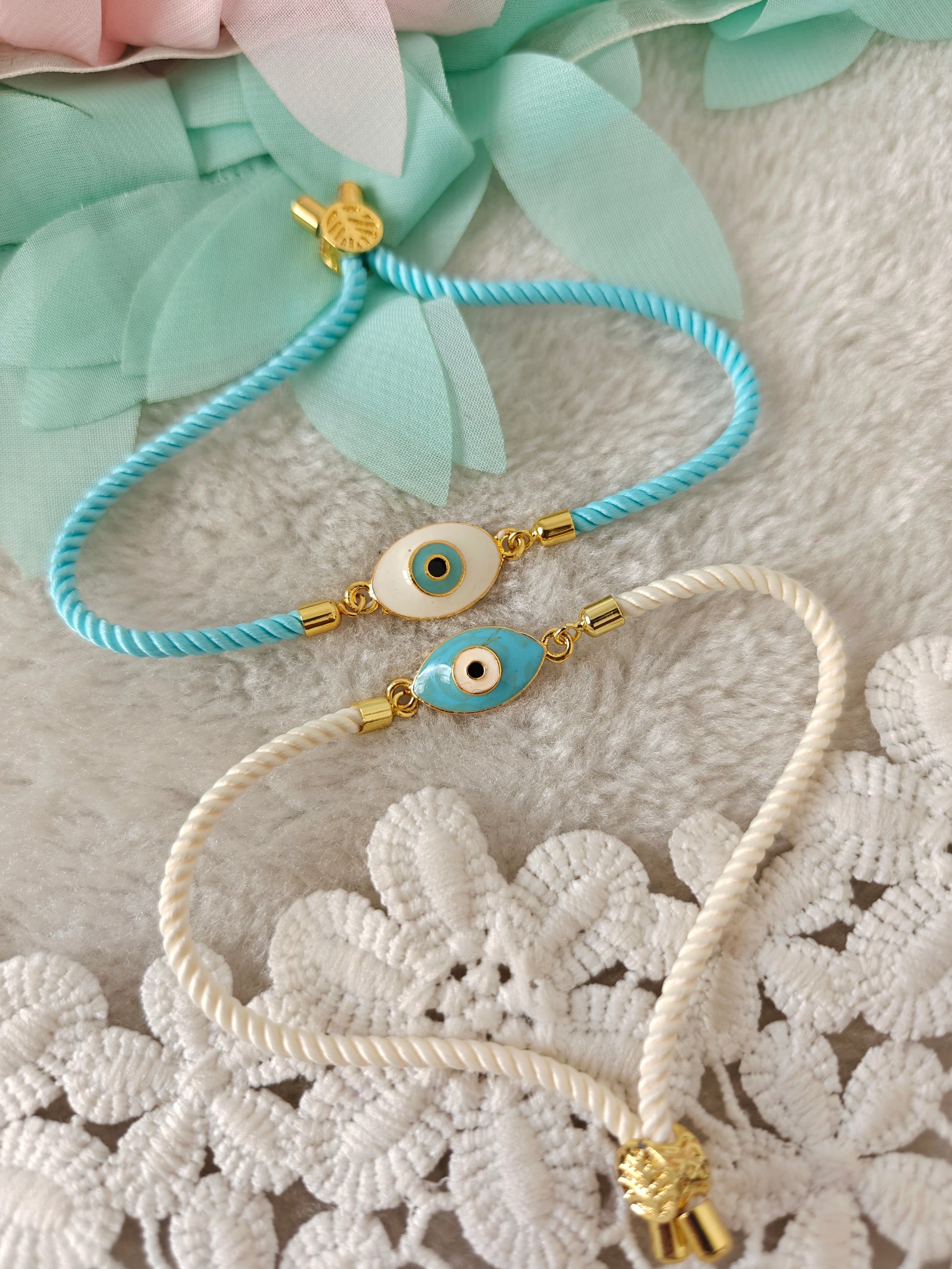 Evil eye bracelet rakhi with oval charm and adjustable rope threads in blue and white on soft background