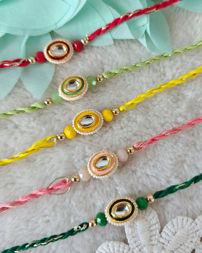 Classic oval rakhi with pearl border, mirror stone and colorful threads on soft background