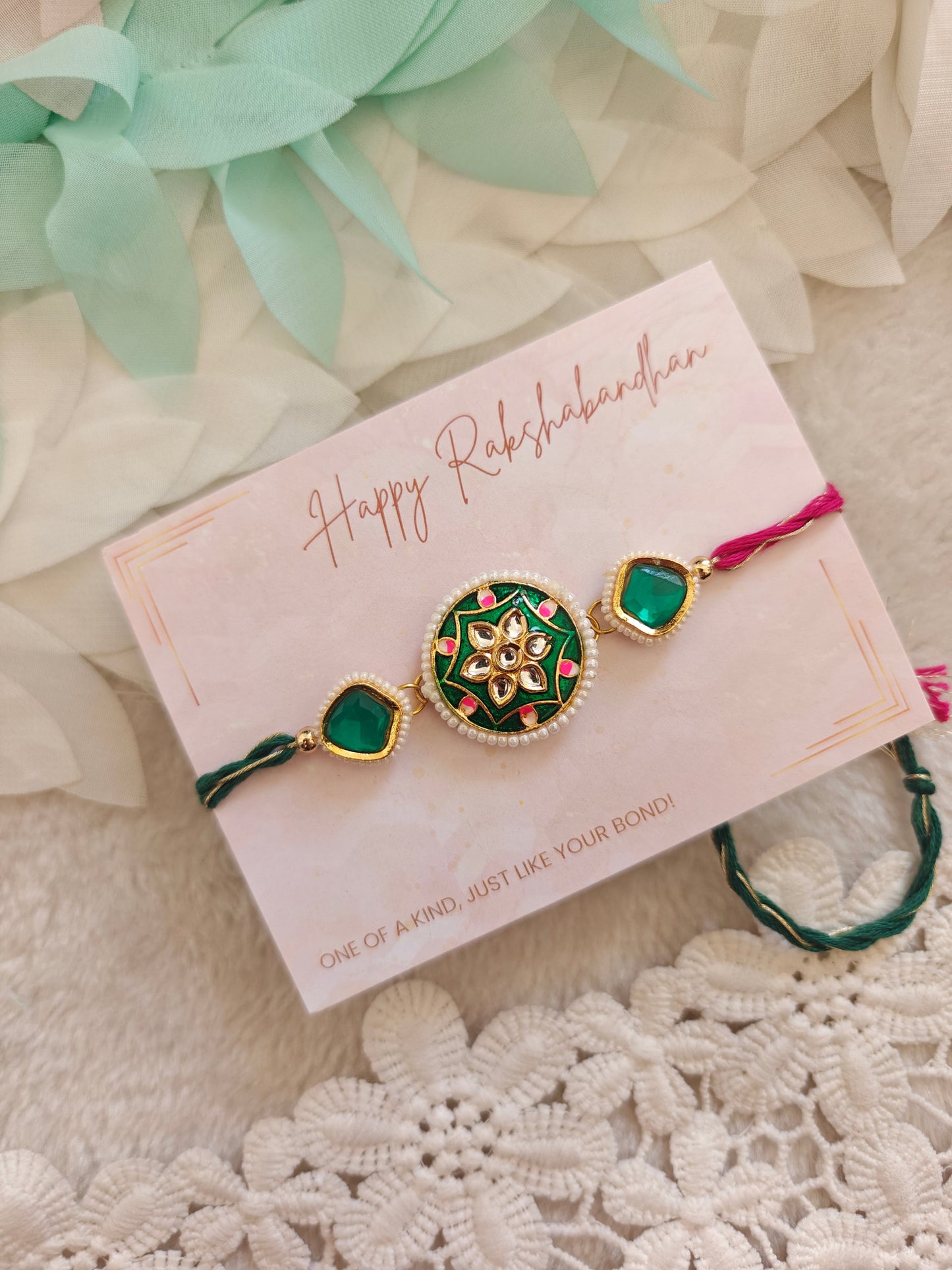 green floral kundan rakhi with pearl border and dual tone threads